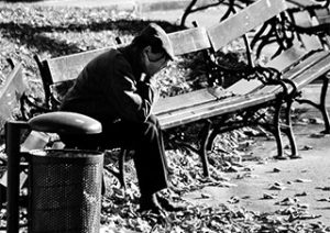 man sitting by the bench with face in hands